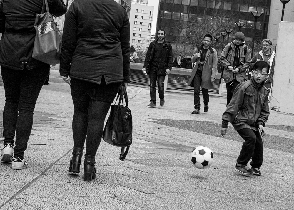 a young boy playing football on the street